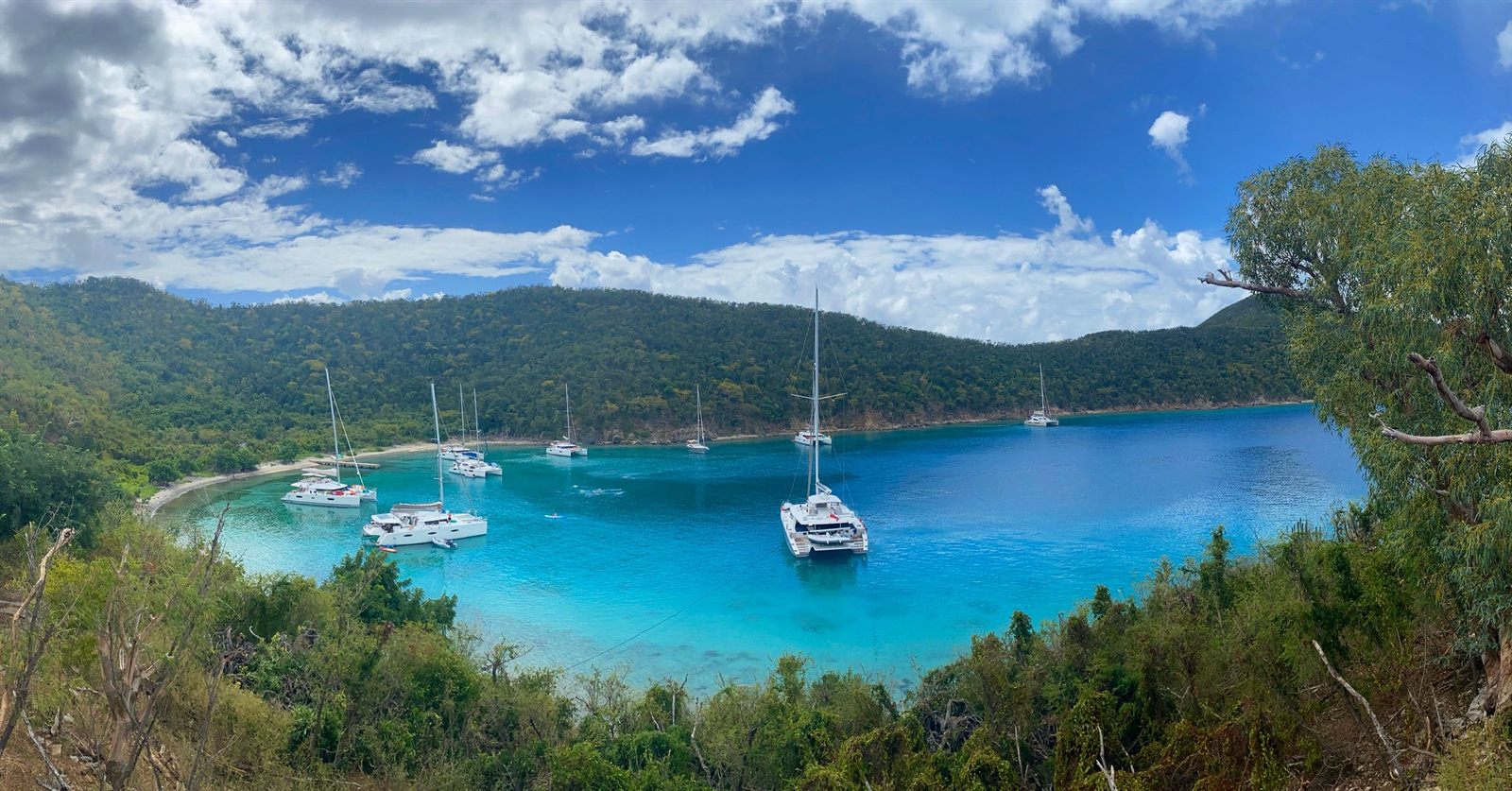 Sailboats anchored in a turquoise bay ringed by green hills in the British Virgin Islands